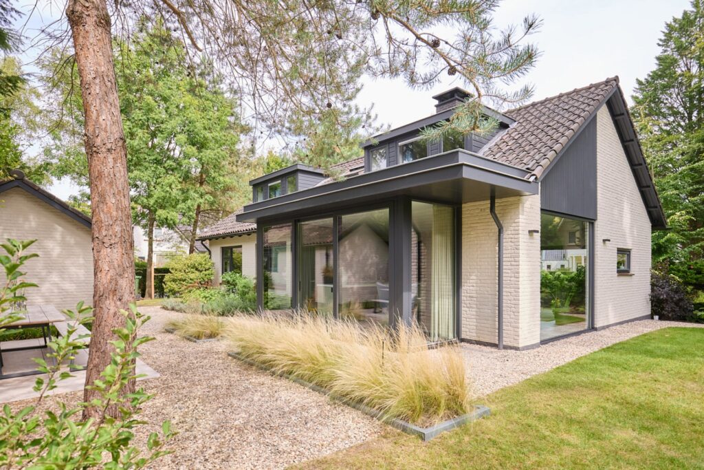 Architectuur van vrijstaande woning met moderne aanbouw en grote glazen puien, project van Groen + Schild Wonen.